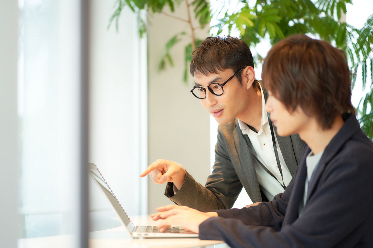 パソコンを見ながら話す二人の会社員