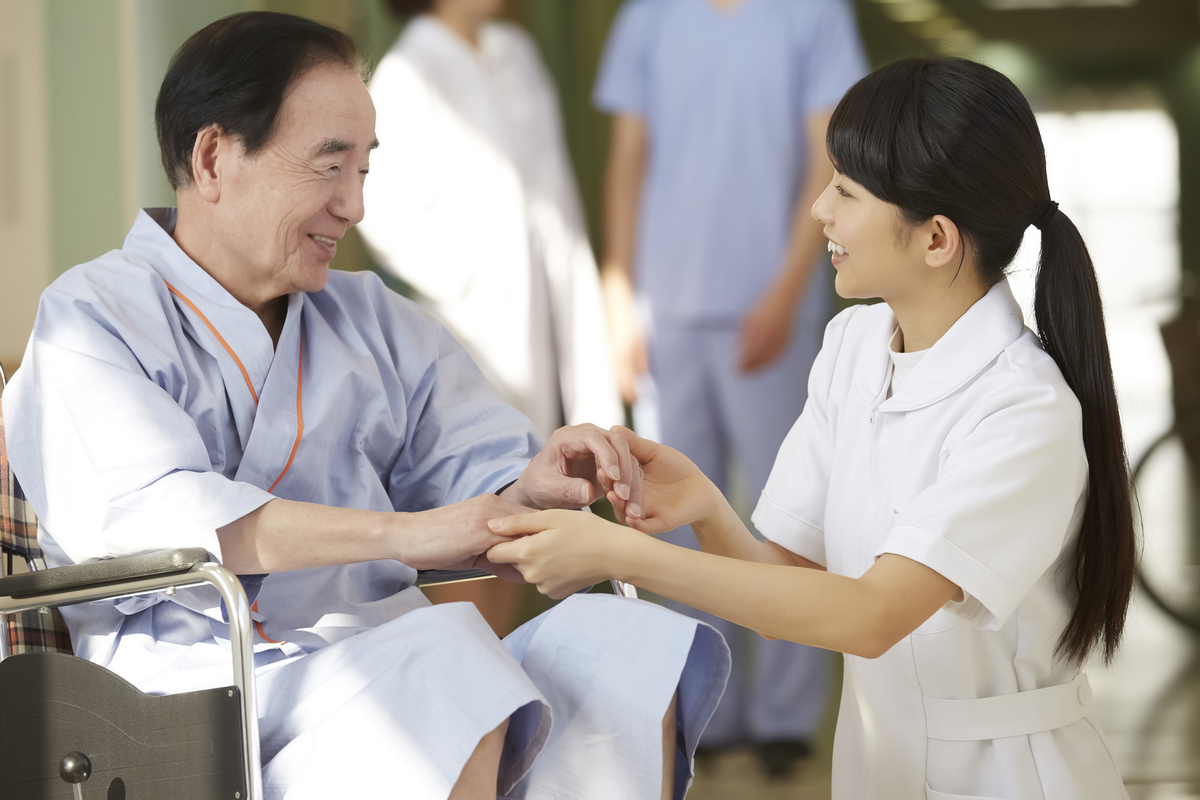 患者の手を取る看護師の女性