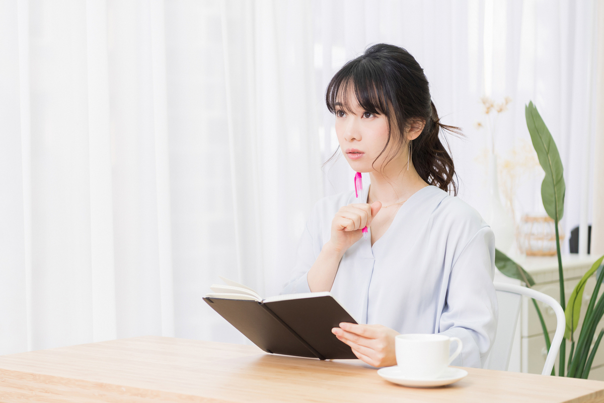 ノートを手に考える女性