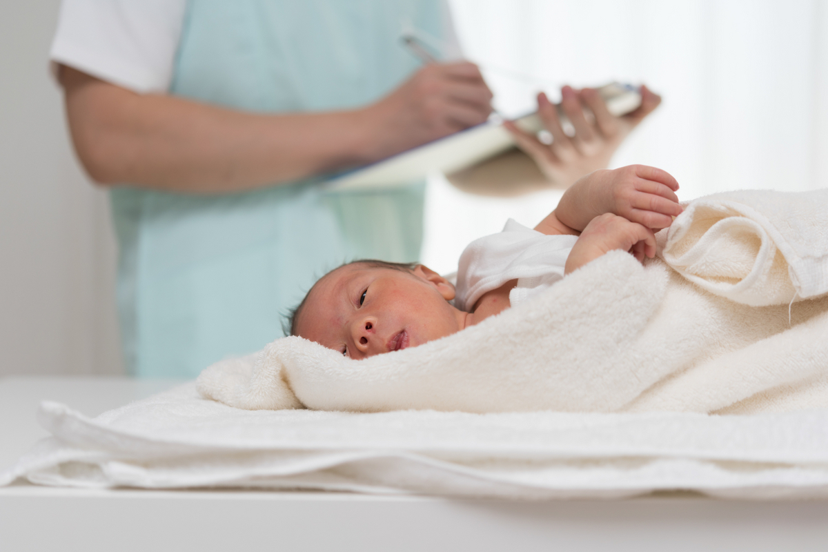 新生児の体調をチェックする看護師