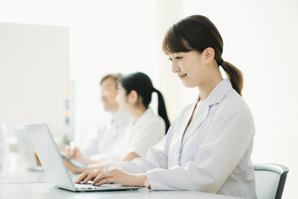白衣を着てパソコンを操作する女性