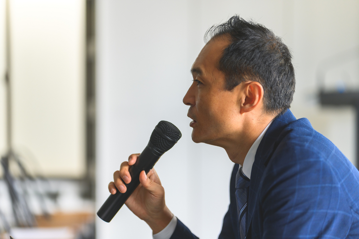 マイクを手に話す男性