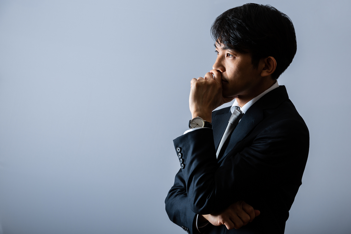 考え事をするスーツの男性