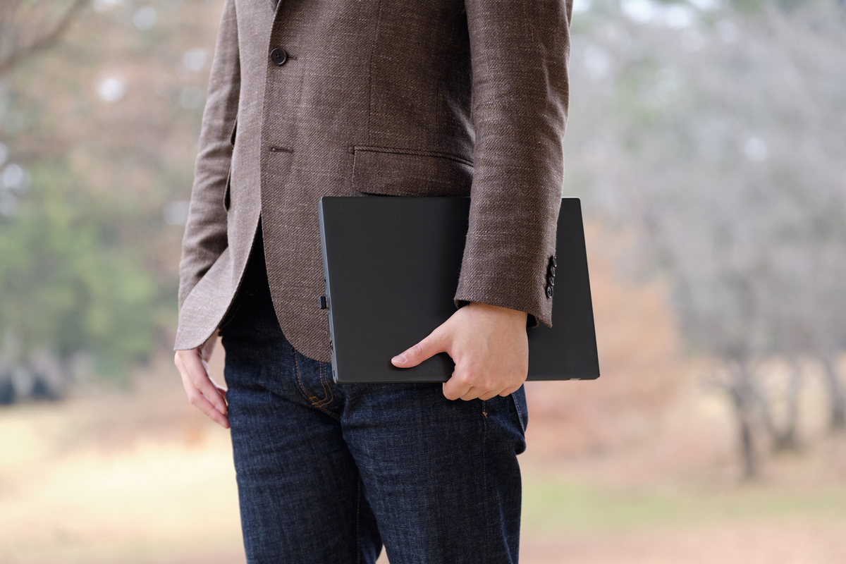パソコンを手に外を歩く男性