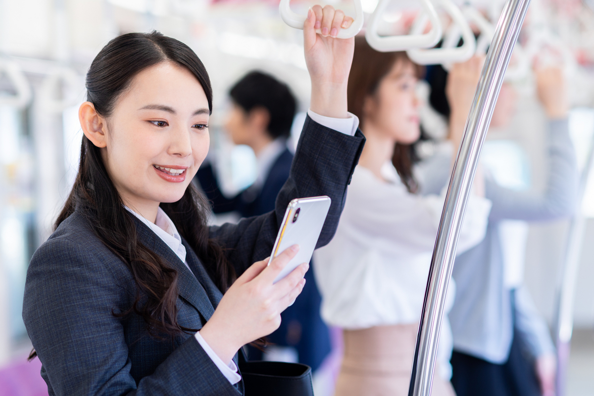 電車でスマホを見ている会社員