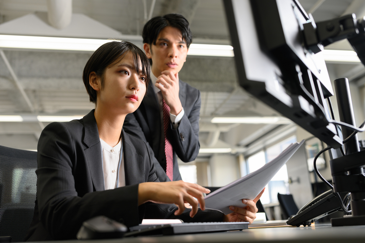 パソコンの画面を見ている会社員２人