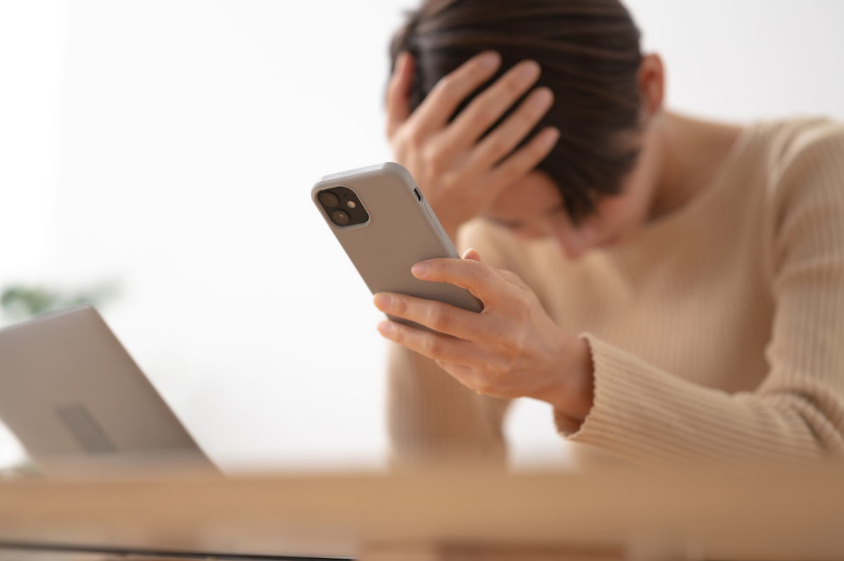 スマホを手に頭を抱える