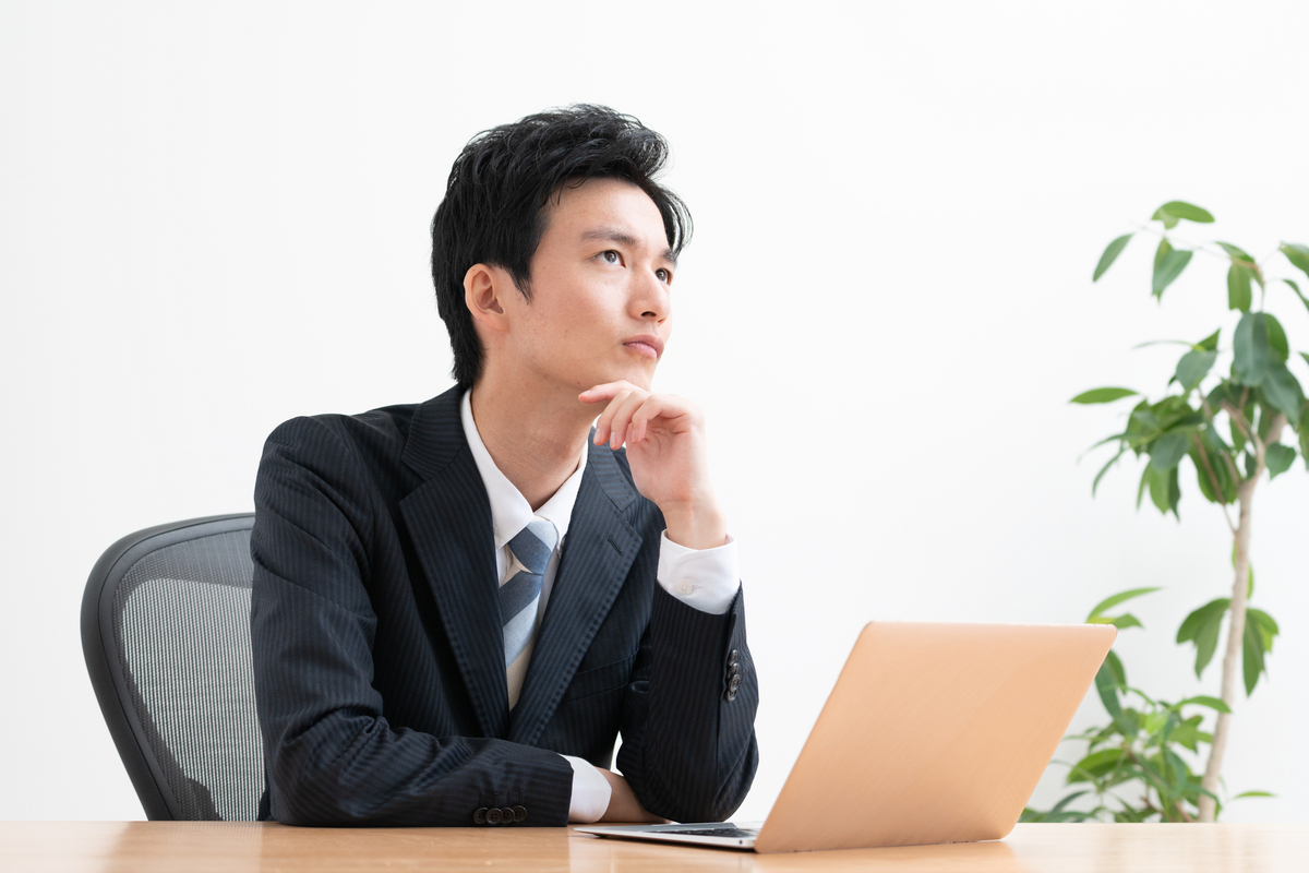 パソコンを前に考え事をするビジネスパーソン