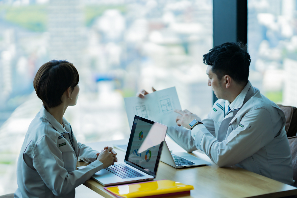 打ち合わせをする作業着の二人のエンジニア