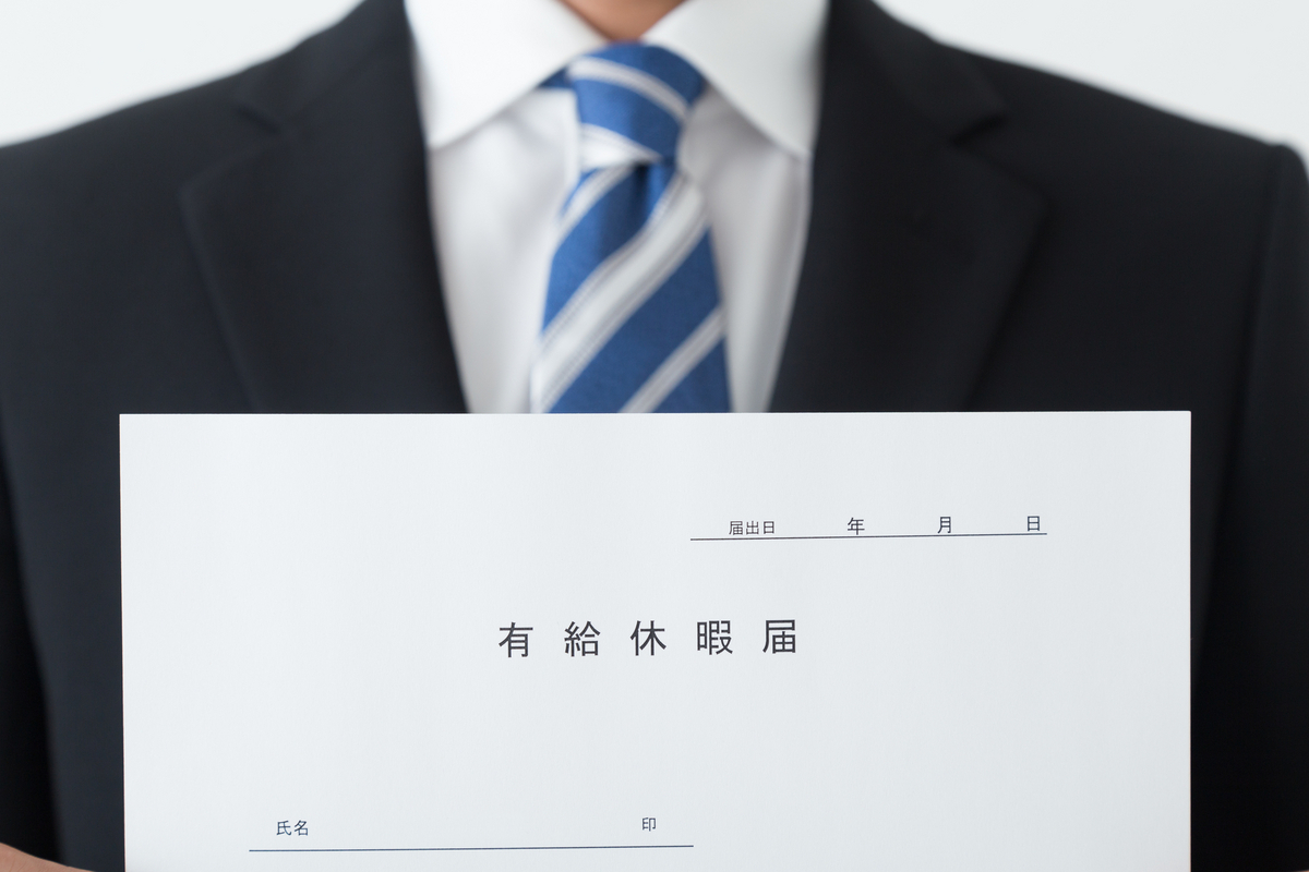 有給休暇届を持つスーツの人物