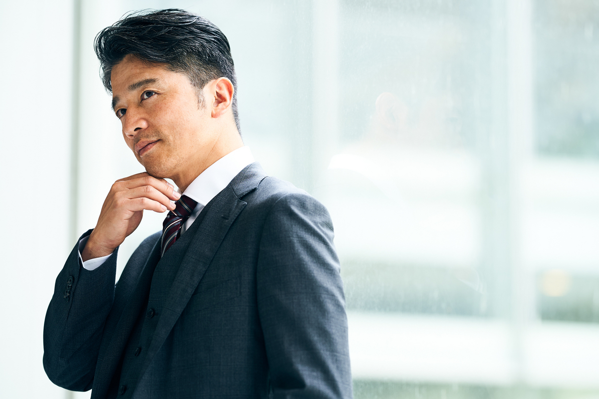 顎に手を当てるミドルのビジネスパーソン