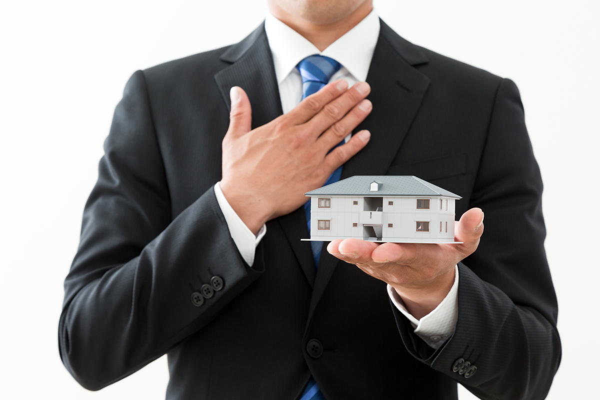 スーツ姿でマンションの模型を持つ人物