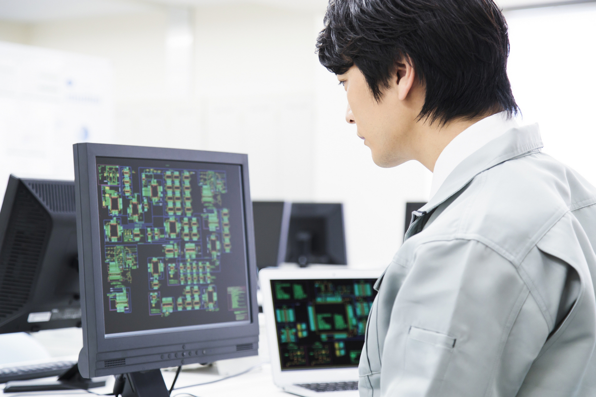 パソコンを見ている作業着の人物