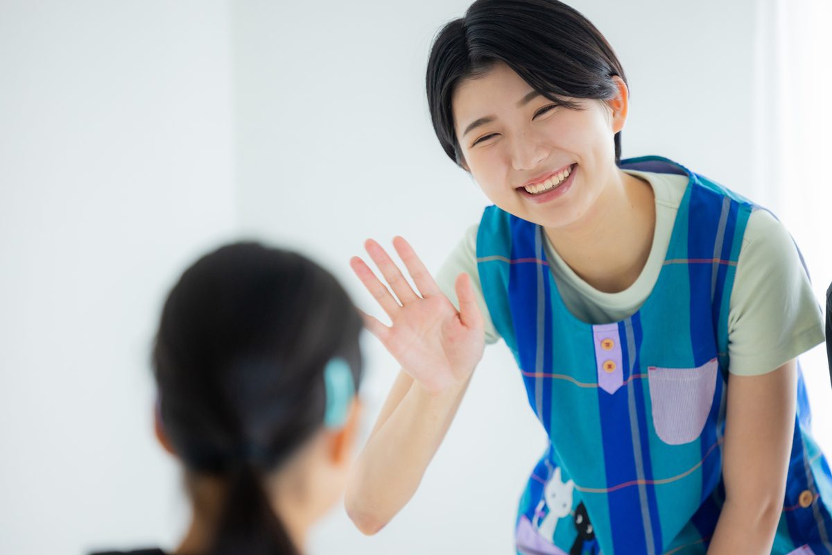 園児を見送る保育士