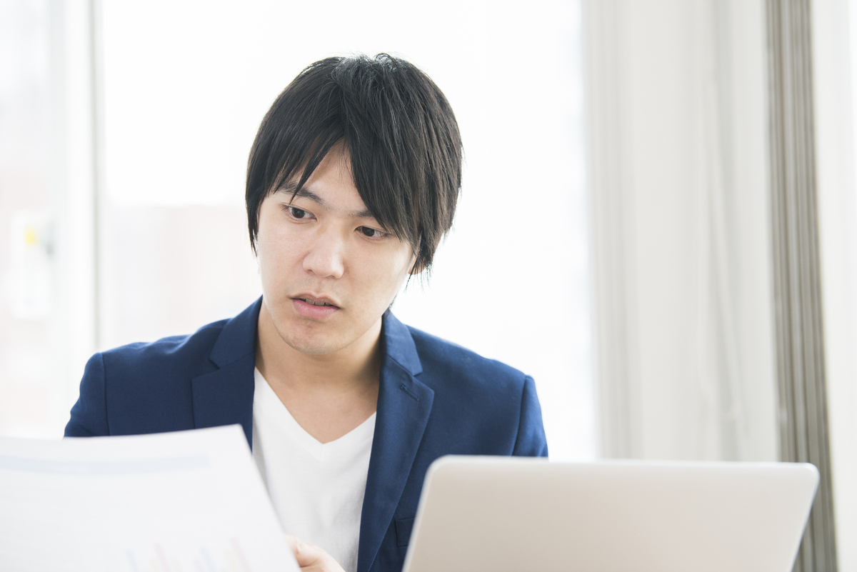 資料とパソコンを見る人物