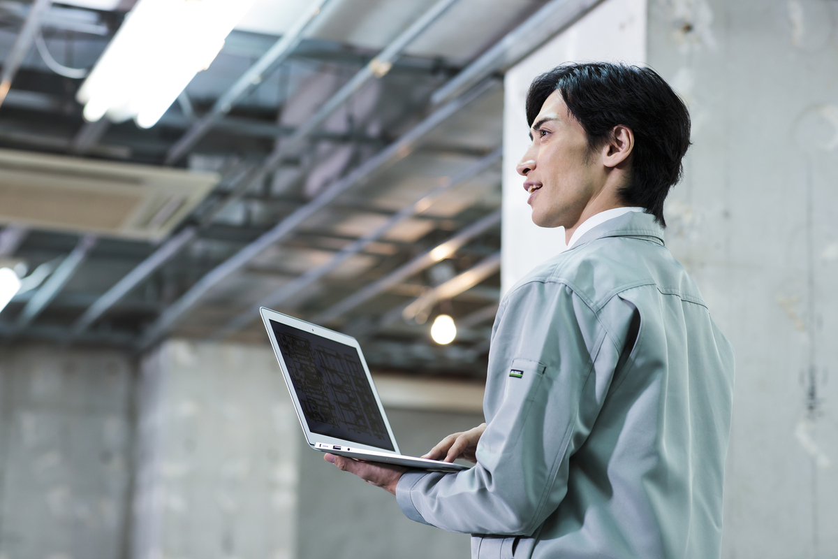 パソコンを手に作業をする人物