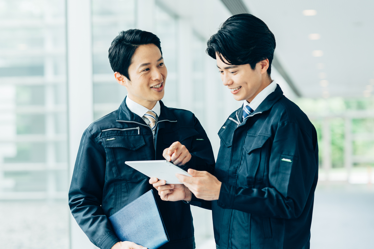 会話をする二人の作業着の人物