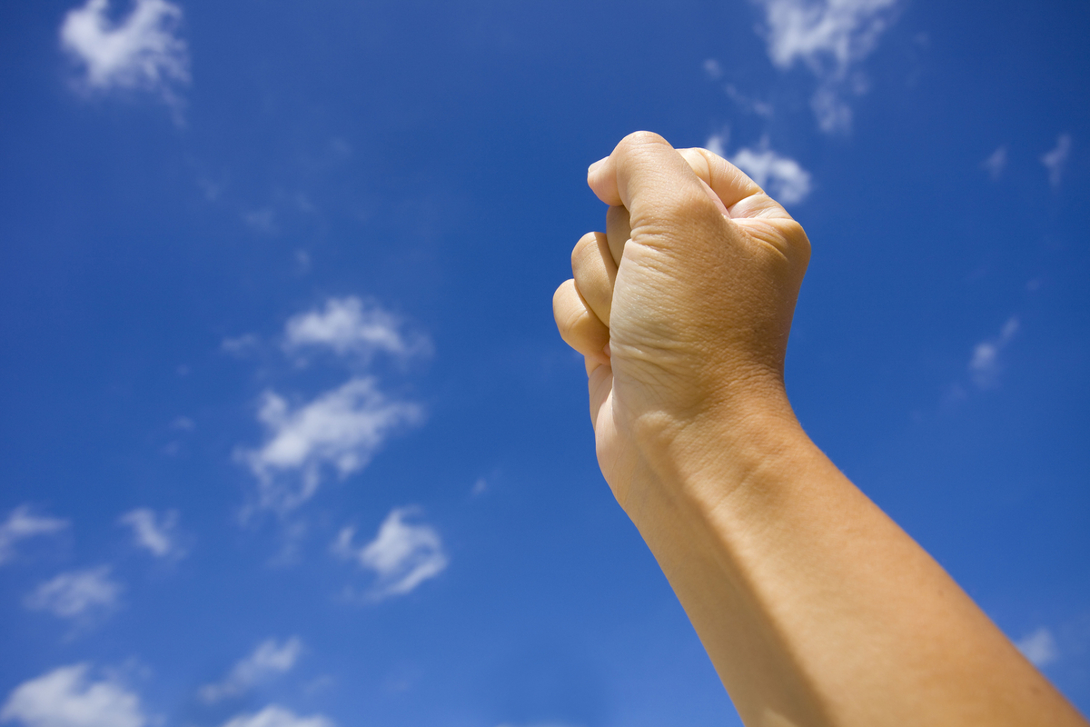 握りこぶしを空に掲げる