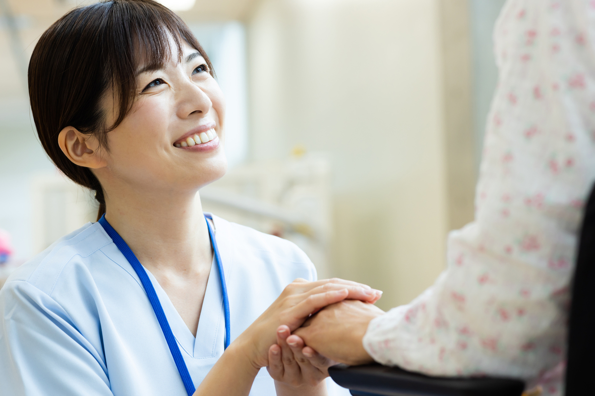 しゃがんで患者の手を握る女性看護師