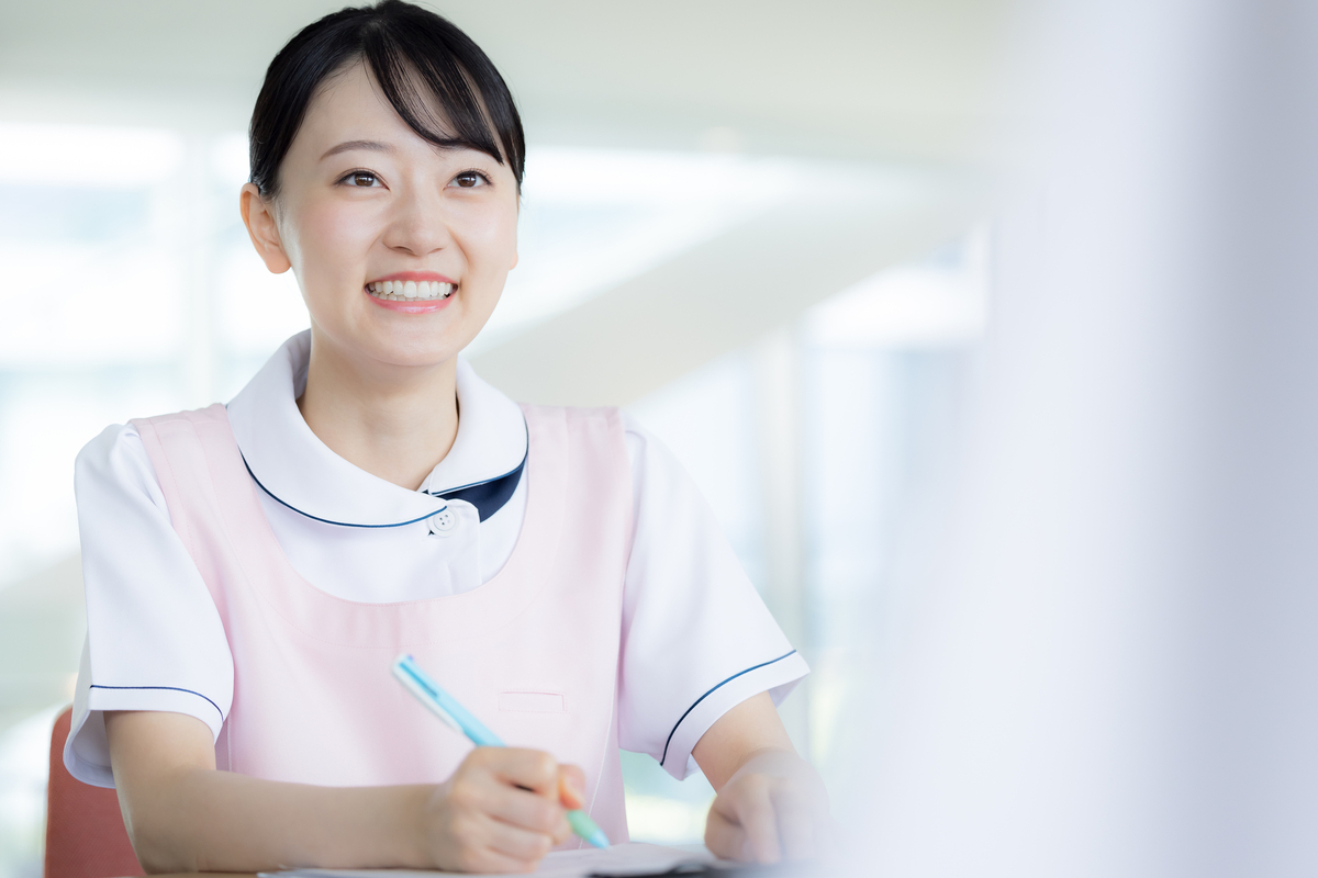 笑顔でメモを取る女性看護師