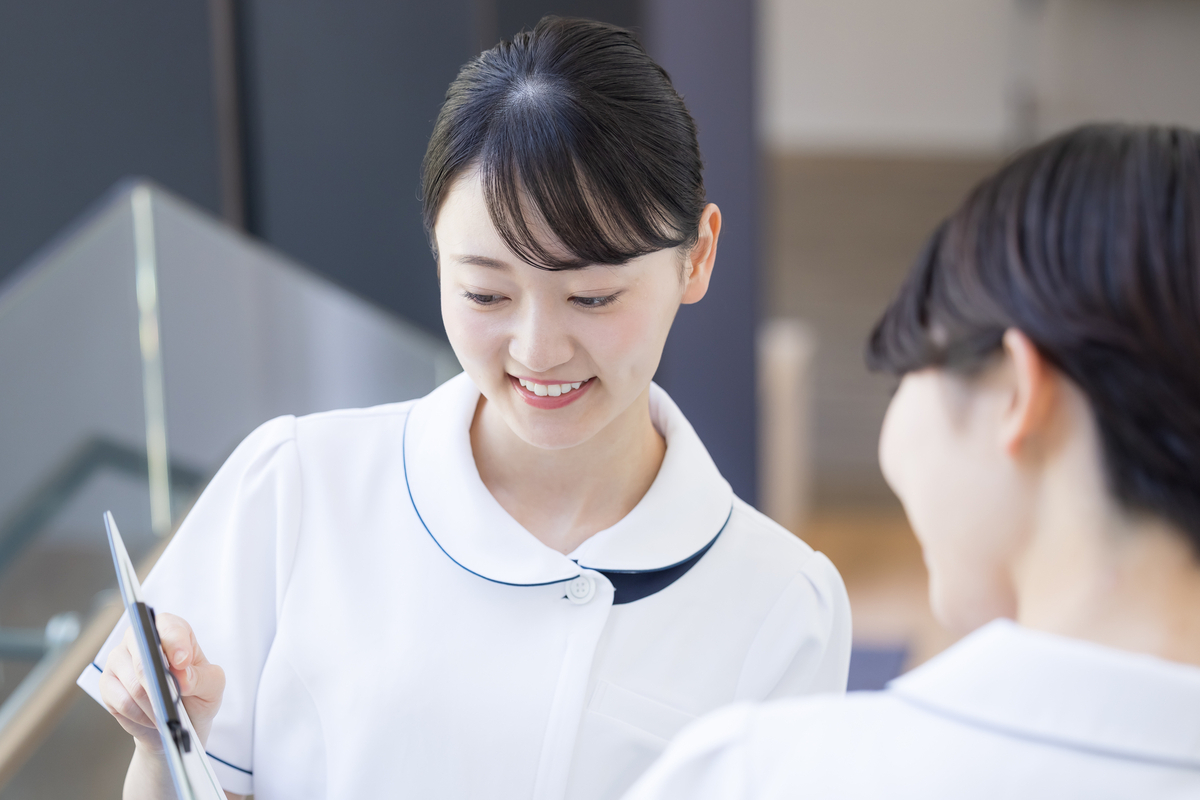 笑顔でタブレットを見ながら会話する看護師