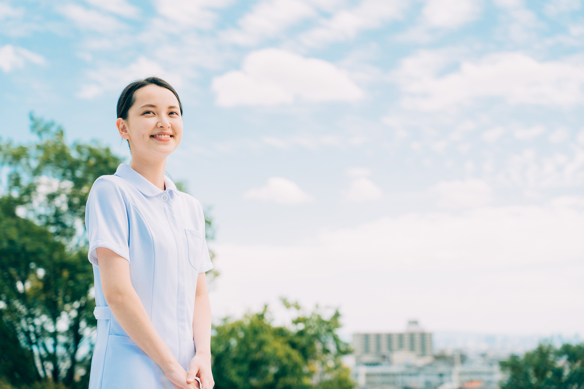 青空の下で微笑むナースの姿の女性
