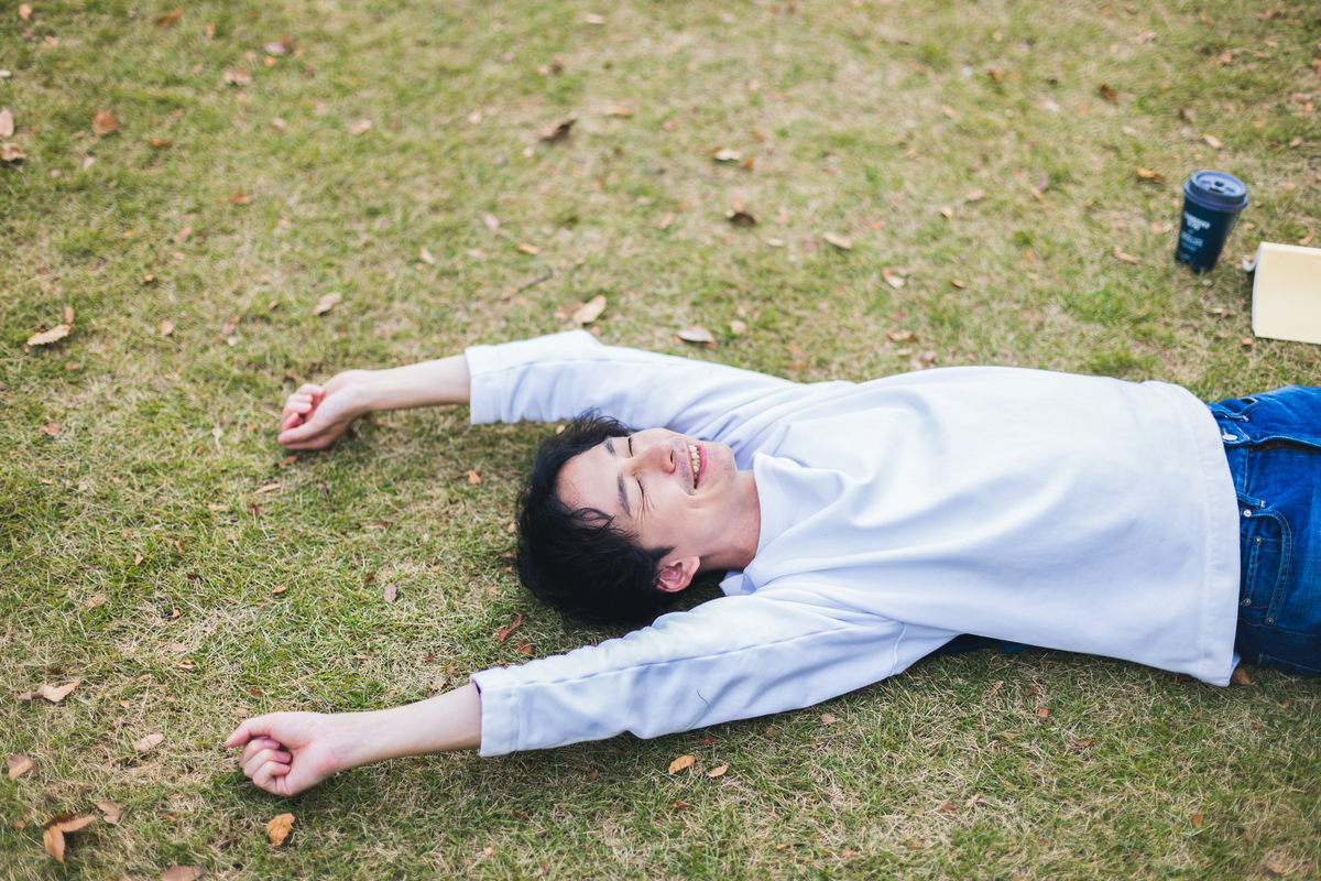 芝生の上で伸びをする男性