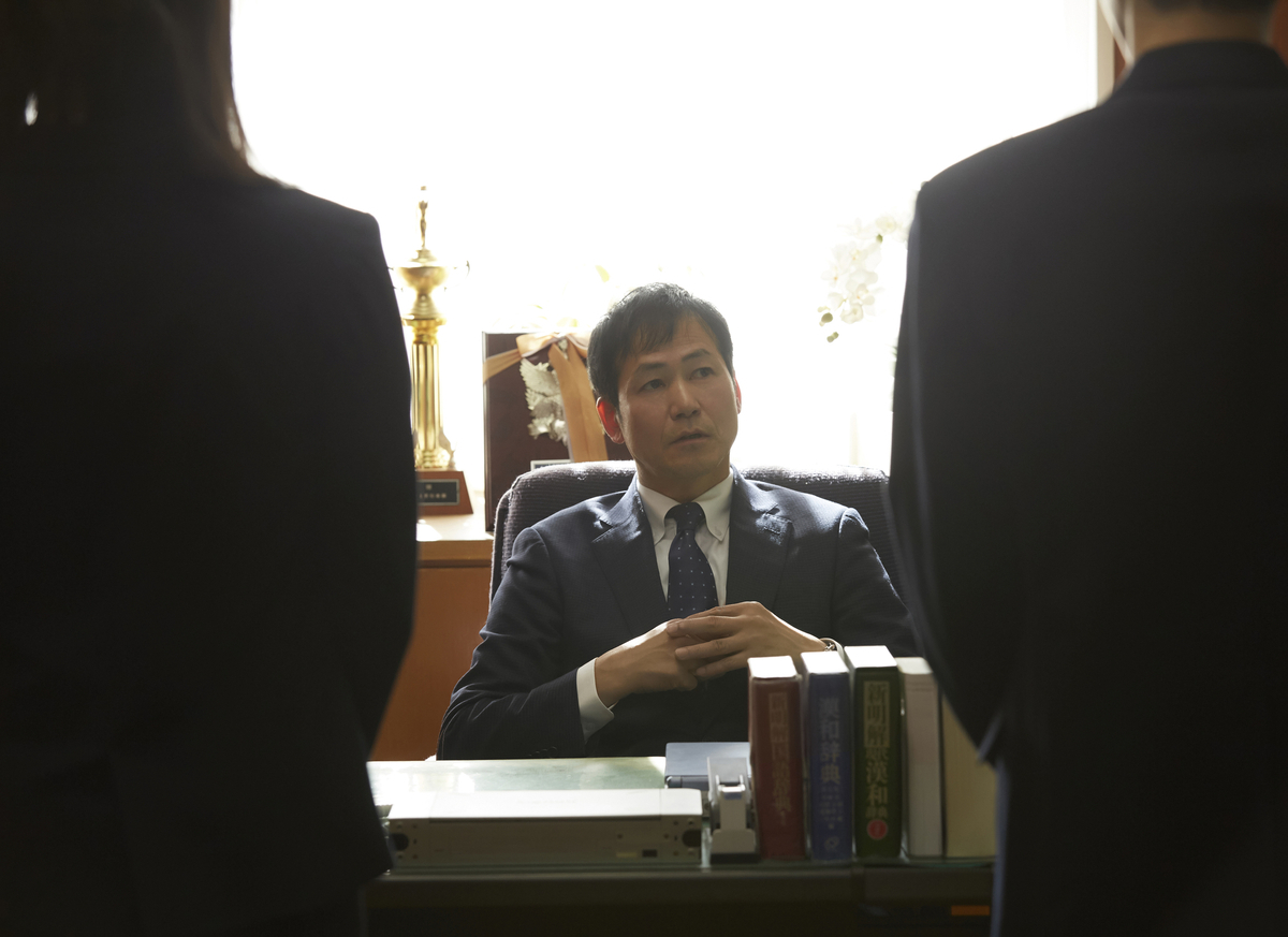 校長と対面する二人の教師