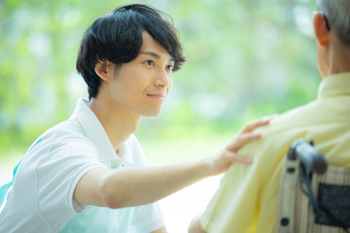 車いすの男性を見る男性職員