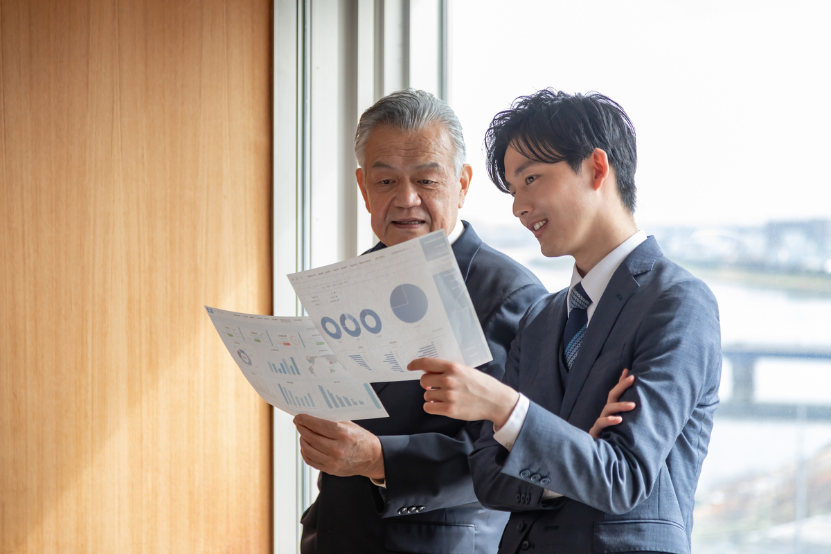 企画書を手に話をする若手社員と中堅社員