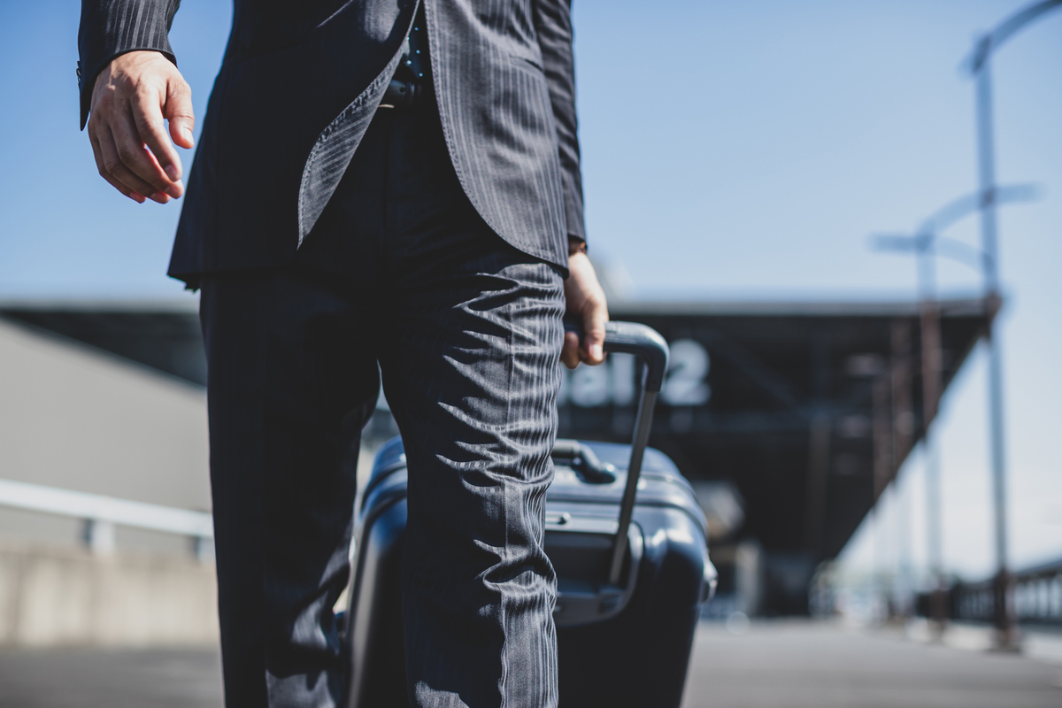 スーツケースを引くビジネスパーソン