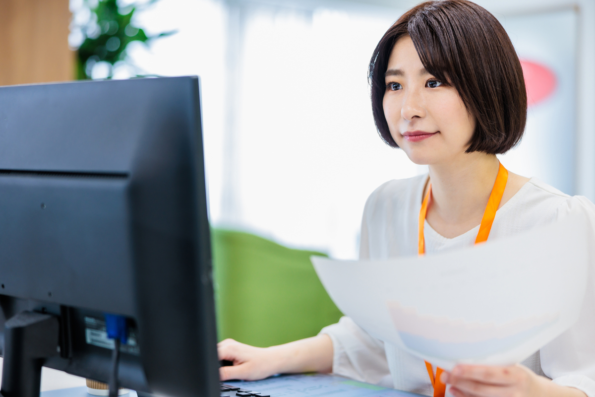 資料を見ながらパソコン作業をする女性