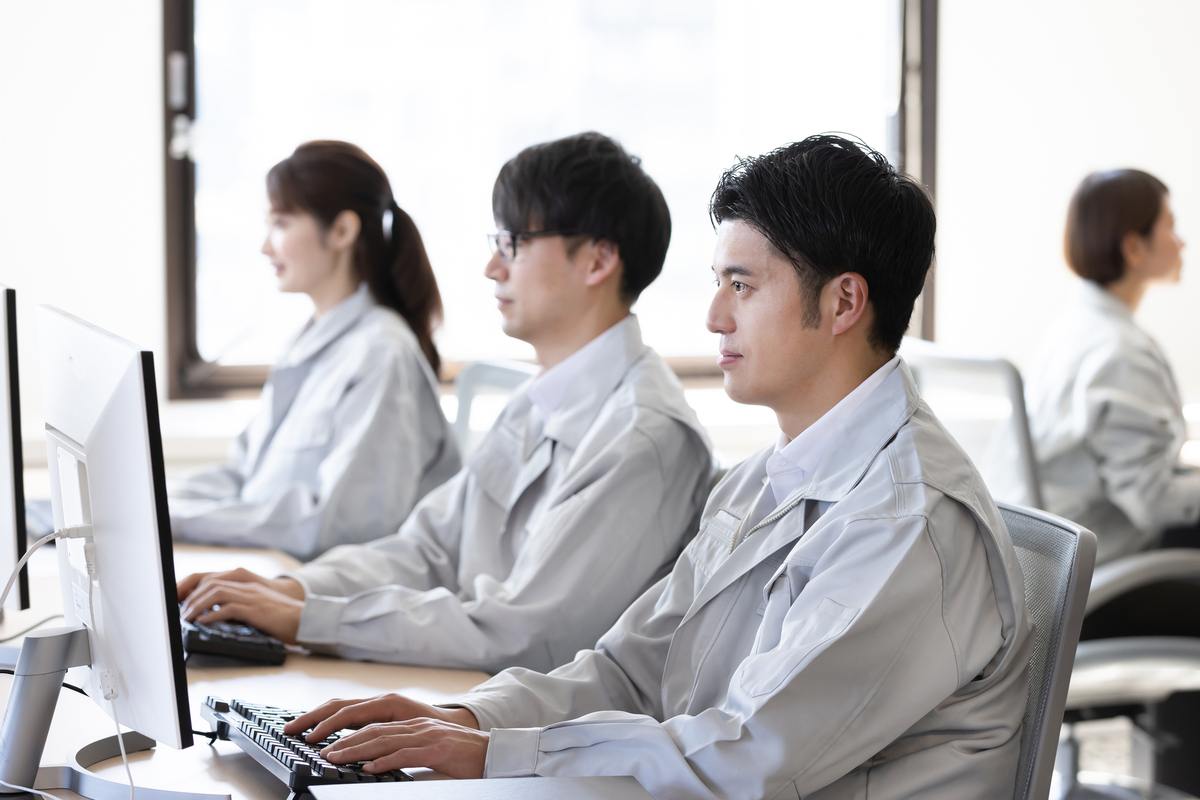 オフィスでパソコン作業する作業服の人たち