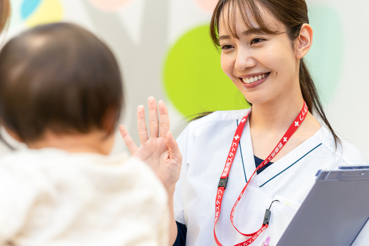 赤ちゃんに手を振る女性看護師
