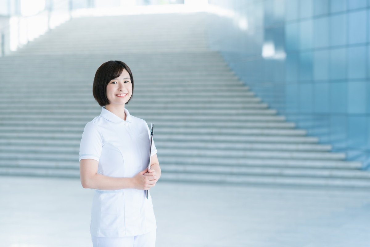 階段の前で笑顔の女性看護師