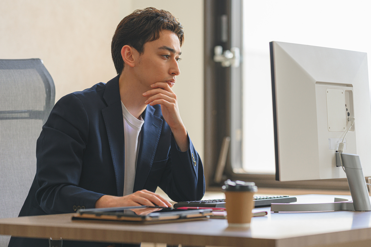 デスクで考え事をする男性