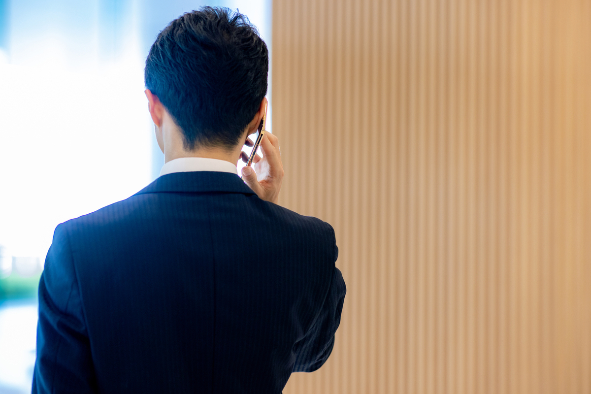 スマートフォンで電話をするビジネスパーソンの後ろ姿