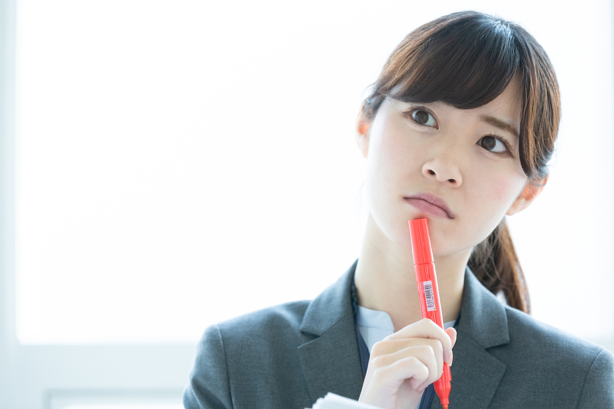 ペンを口元に当てている女性