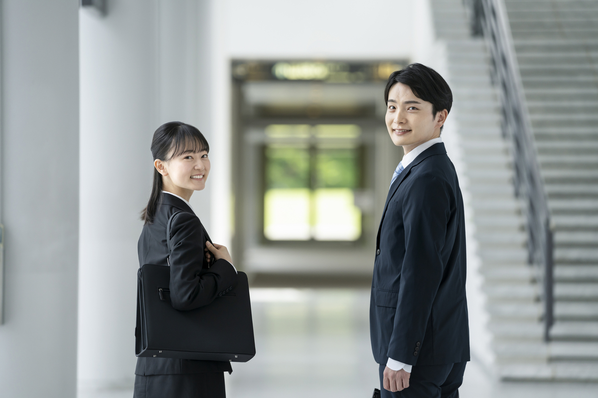 こちらに振り向くスーツ姿の男女