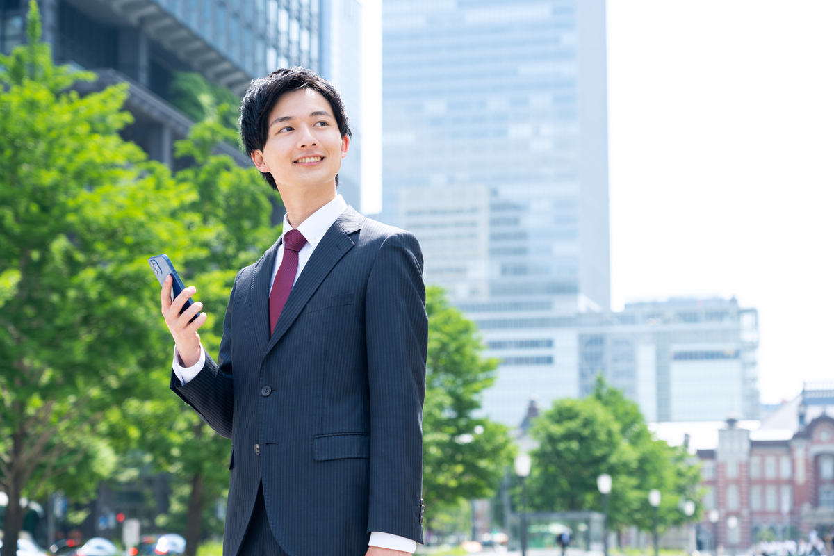 屋外でスマホを持つビジネスパーソン