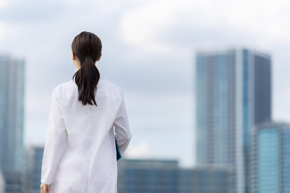 都市を眺める白衣の女性