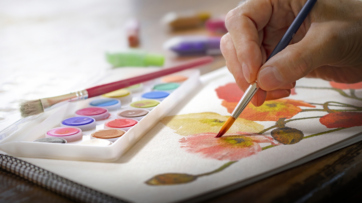 スケッチブックに花の絵を描く人の手元