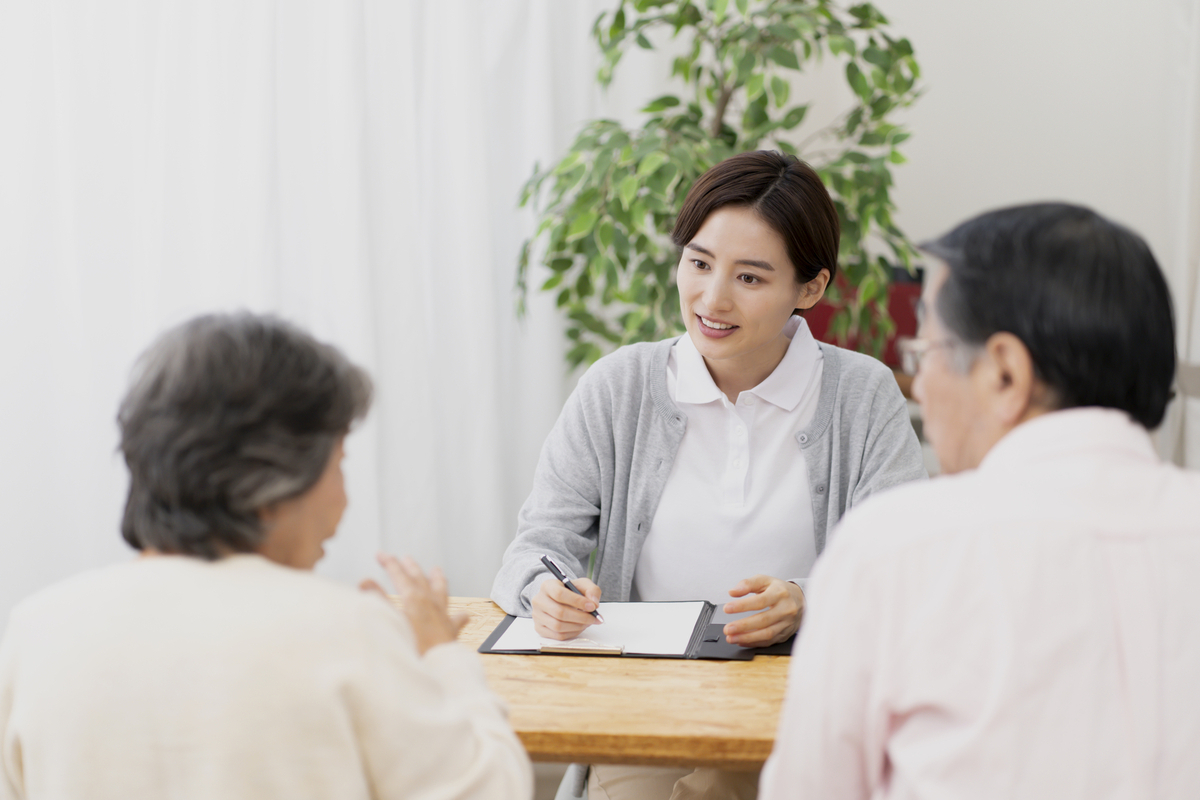 老夫婦と会話する女性医療従事者