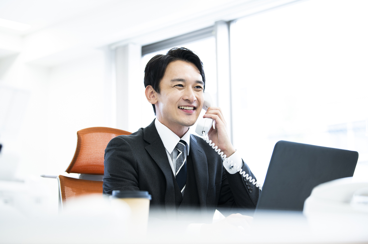 パソコンの前で電話をするビジネスパーソン