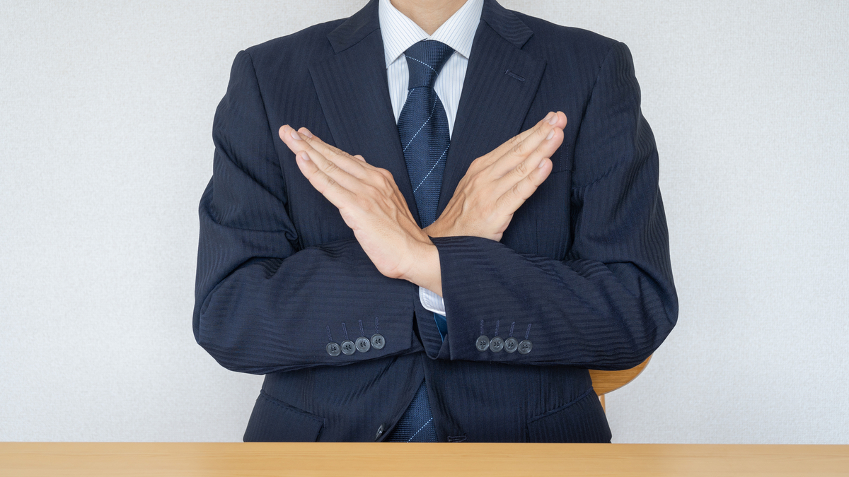 胸の前で✕マークを作る男性