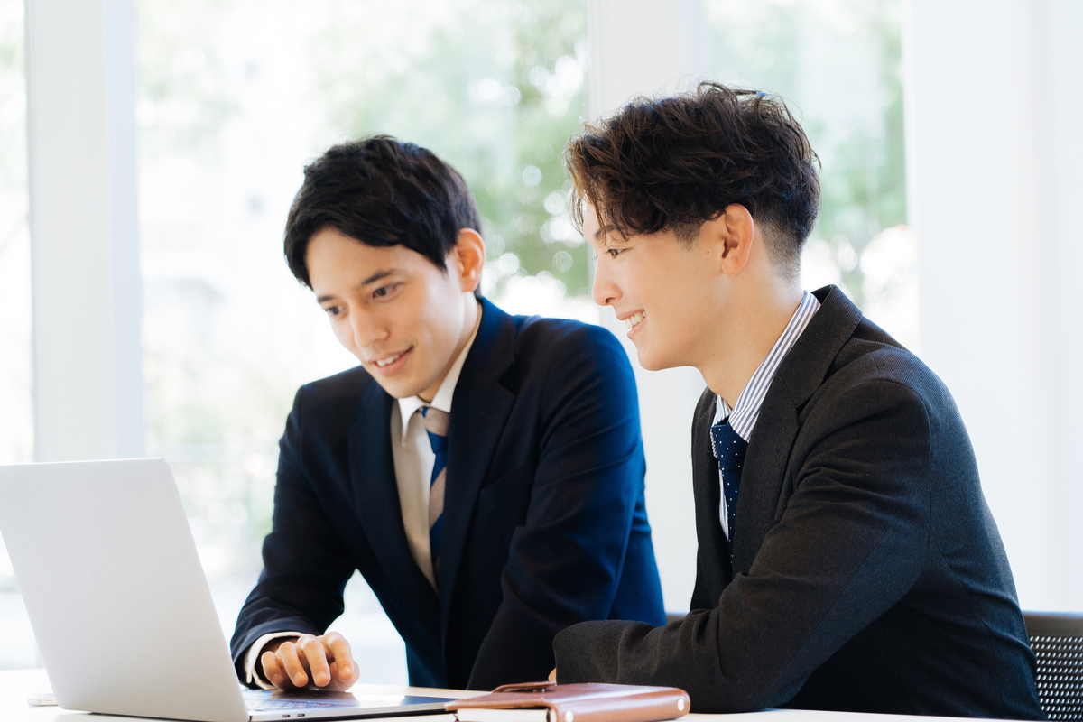 パソコンの前で話す男性2人