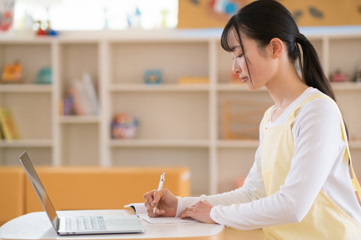 日誌を書く女性保育士