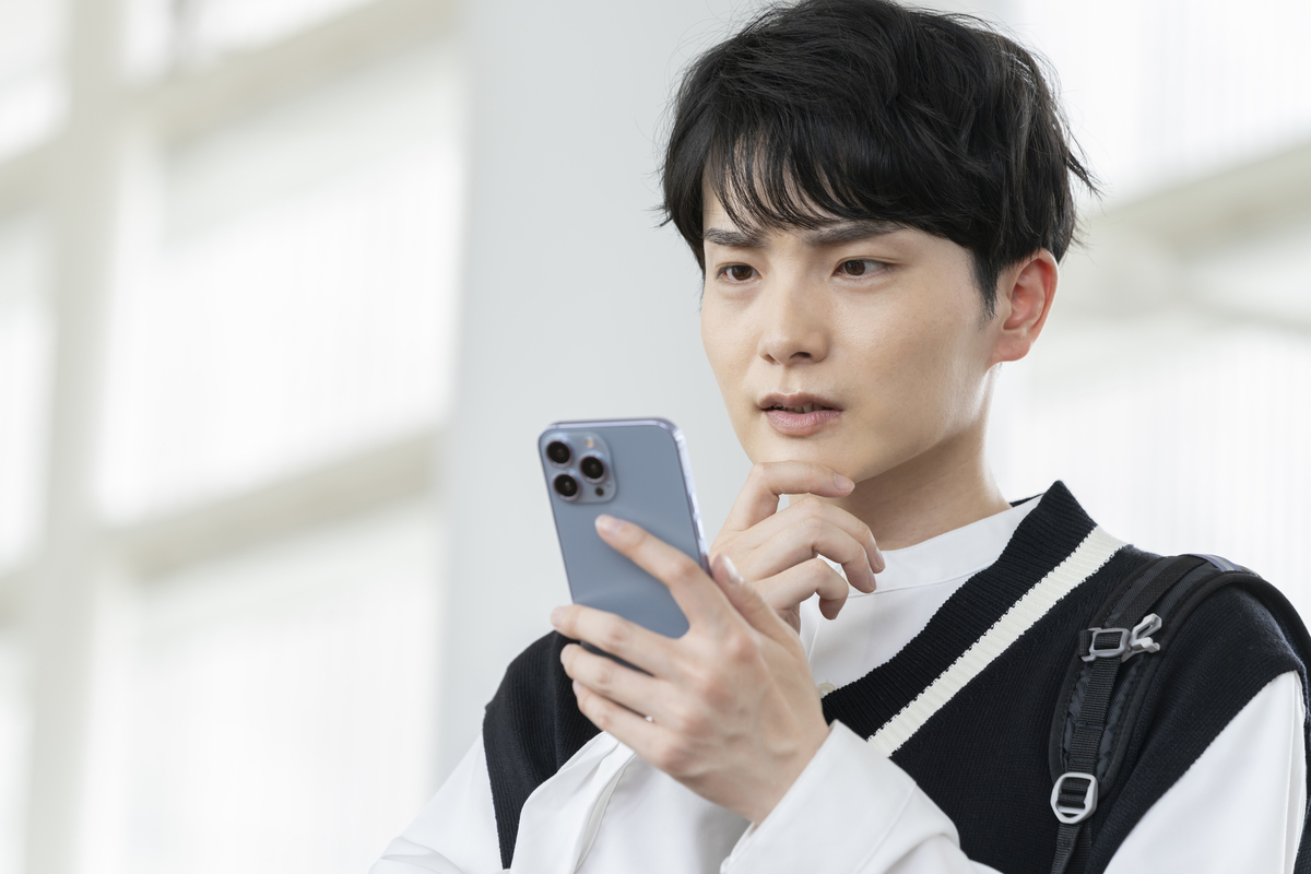 スマホを見ながら考える人物