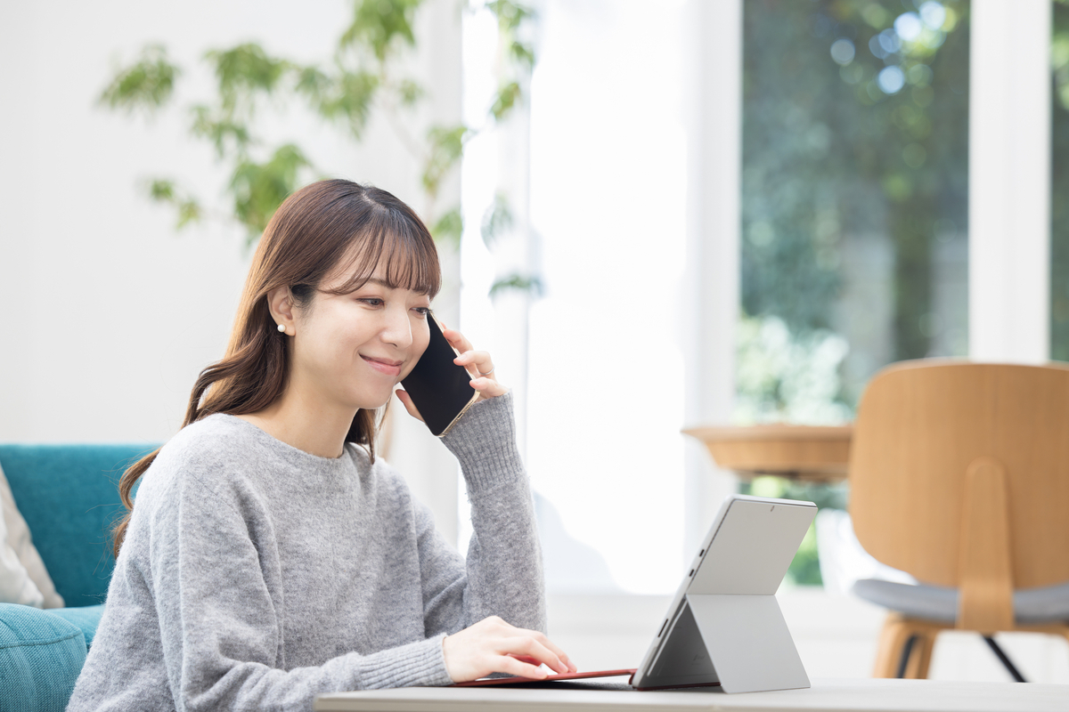 パソコン操作をしながら電話をする女性