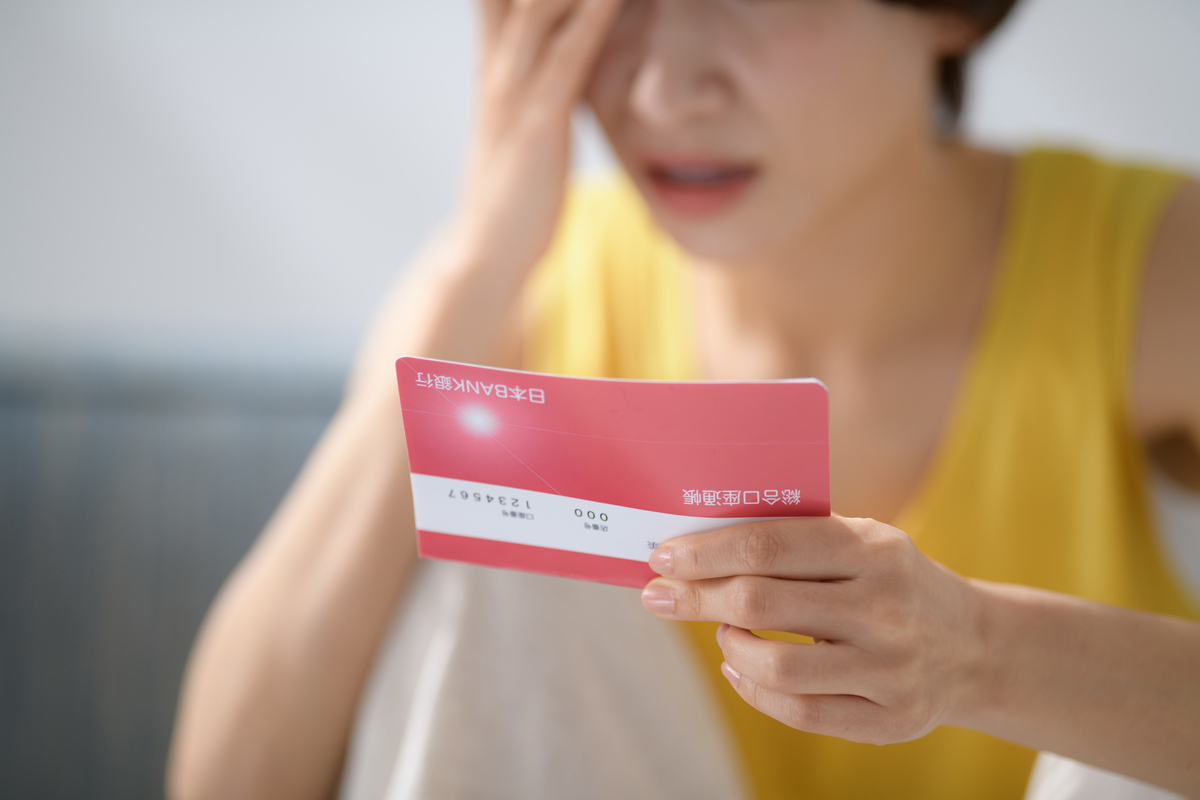 通帳を見て悩む女性